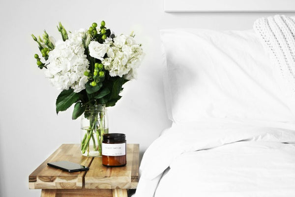 A bedside table next to a bed with grounding bed sheets