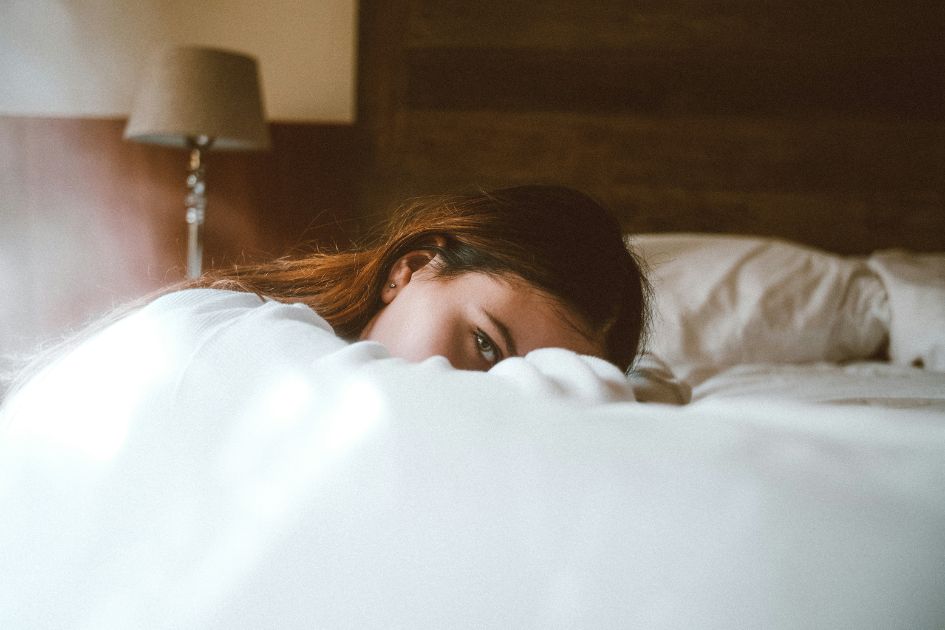 A girl resting her head on her cotton grounding bed sheets