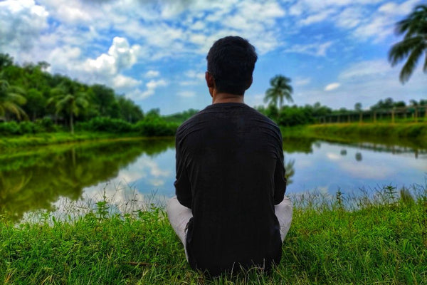 A man sitting on grass enjoying grounding benefits