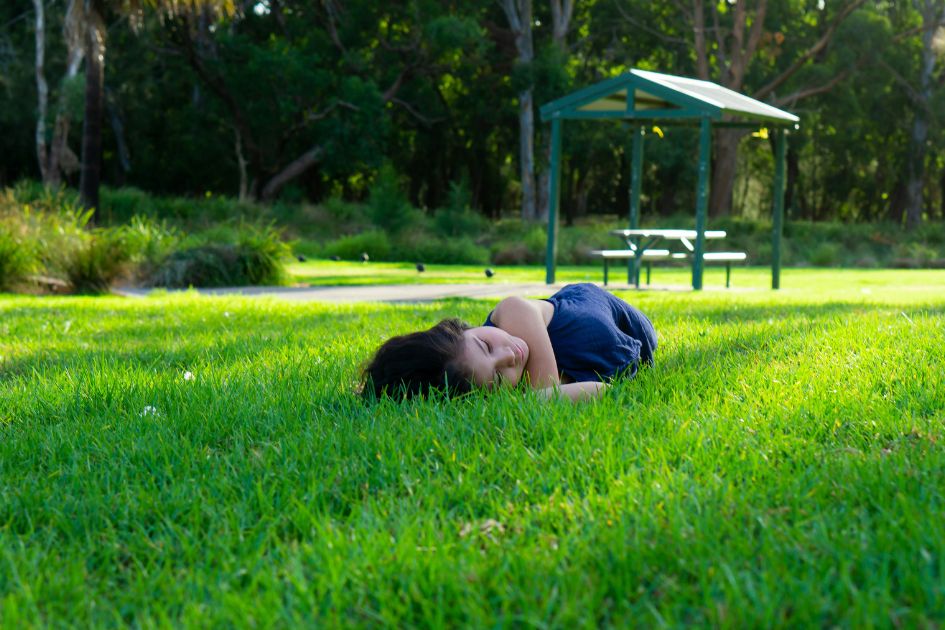 Child on grass illustrating natural grounding connection similar to Restora Dream grounding sheet