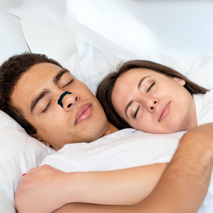 A man sleeping next to his partner and wearing Restora Dream nasal strip