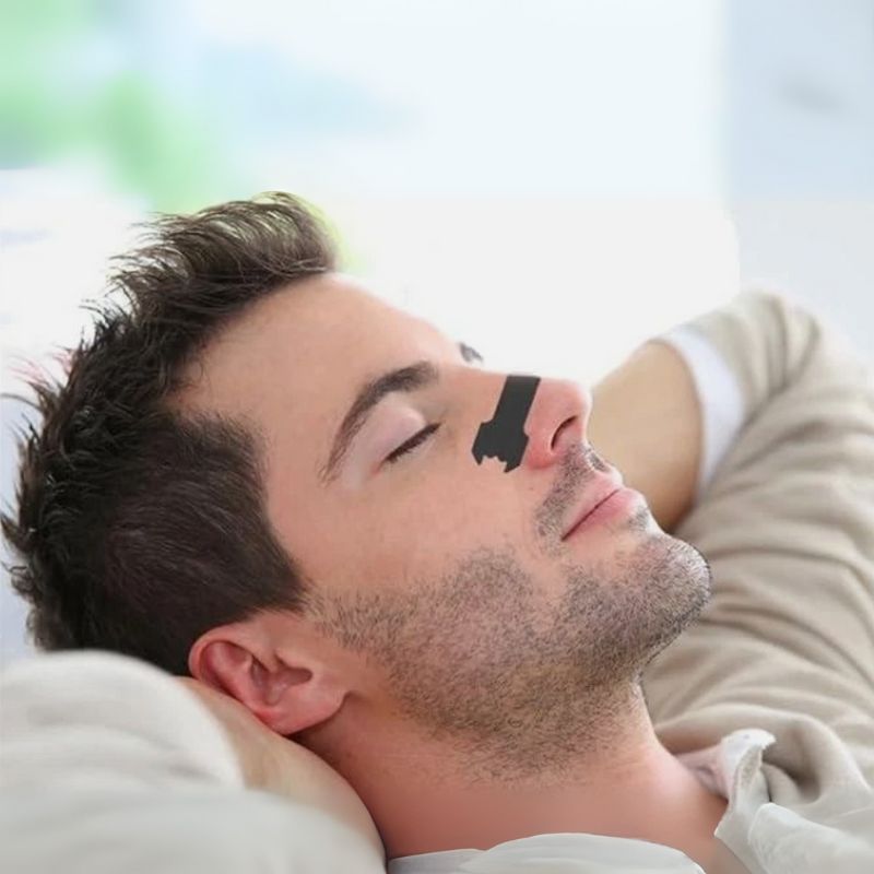 A man using Restora Dream nasal strip for improved airflow restful sleep and reduced snoring
