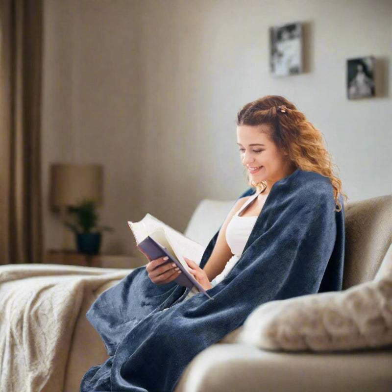 Woman enjoying a book while covered with a grounding blanket for relaxation